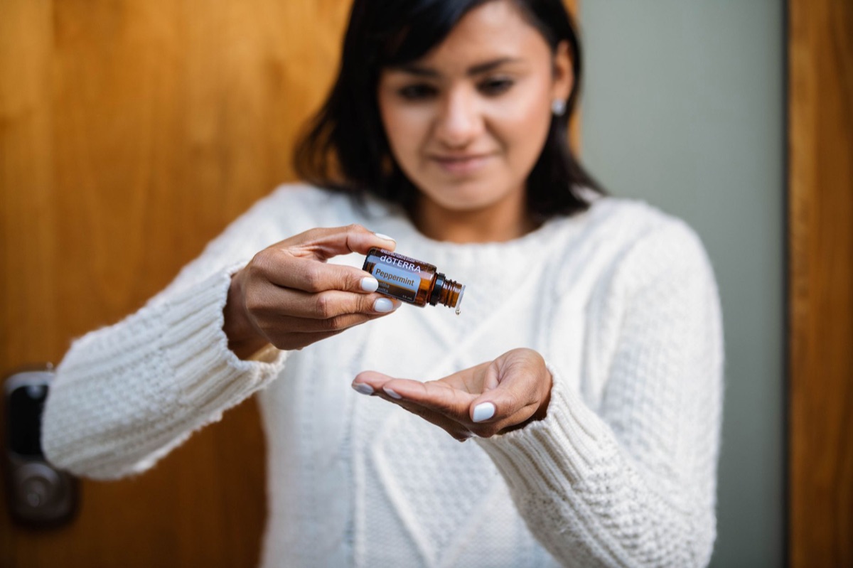 Peppermint oil in hand with a white background