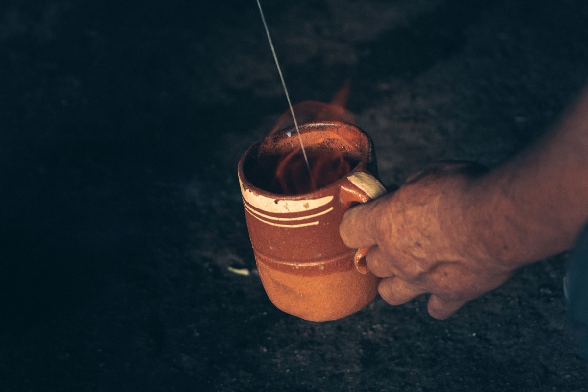 person drinking herbal tea from clay cup