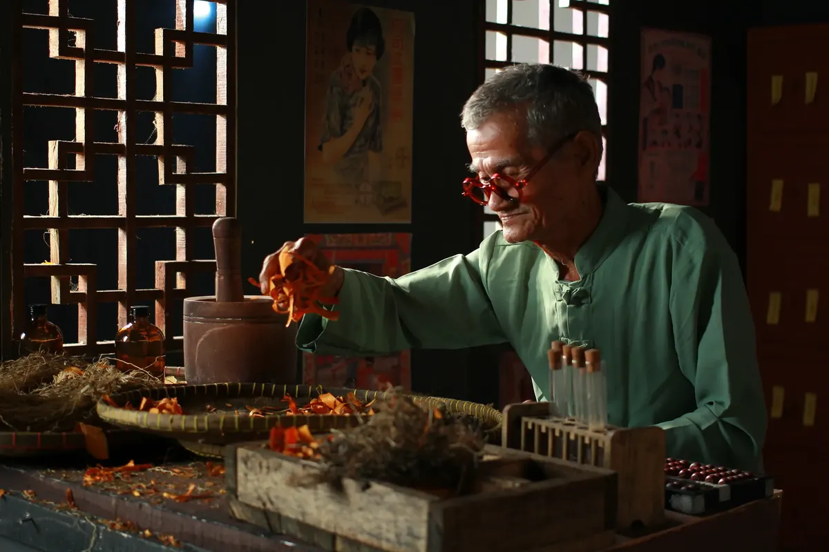 Elderly herbalist preparing traditional medicine at a vintage shop in Jakarta, Indonesia.