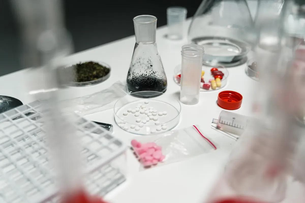 A laboratory table displaying pills, petri dishes, and chemical beakers for scientific research.